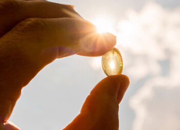 Ein Mann hält eine Vitamin-D-Kapsel in die Sonne.