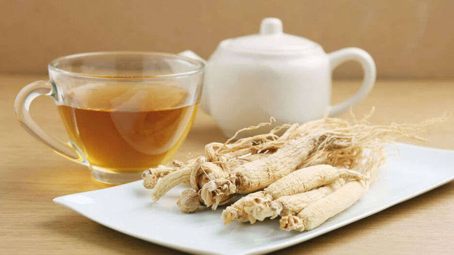 Zubereiteter Tee mit Ginseng und Ginsengwurzeln stehen auf dem Tisch. Ginseng hilft bei Erschöpfung, Müdigkeit und fehlender Konzentration.