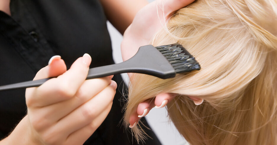 Man sieht wie Farbe mit einem Pinsel in blonde Haare gestrichen wird.