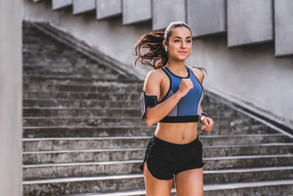 Eine junge Frau beim Laufsport, die in die Kamera lächelt.