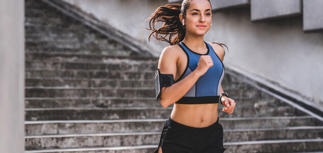 Eine junge Frau beim Laufsport, die in die Kamera lächelt.